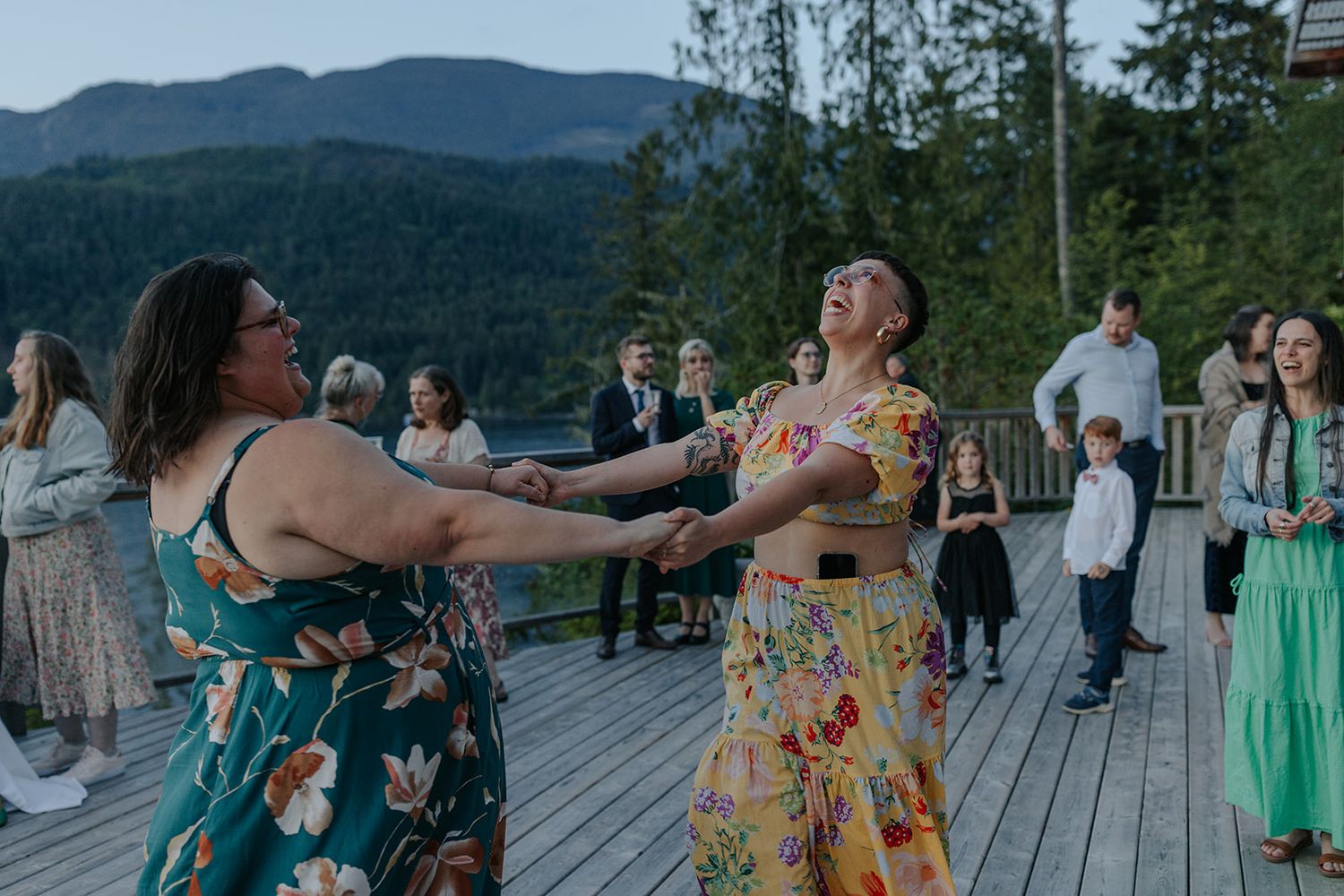 Celebratory dancing at an outdoor mountain venue with scenic forest views.
