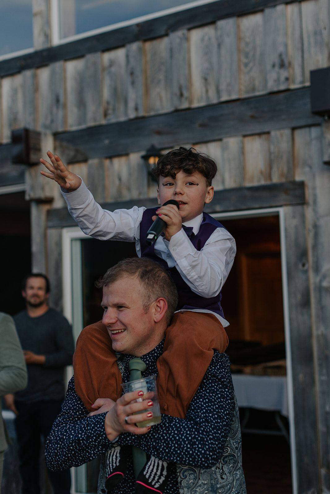 Wedding guests celebrate and dance at an outdoor reception on a wooden deck.