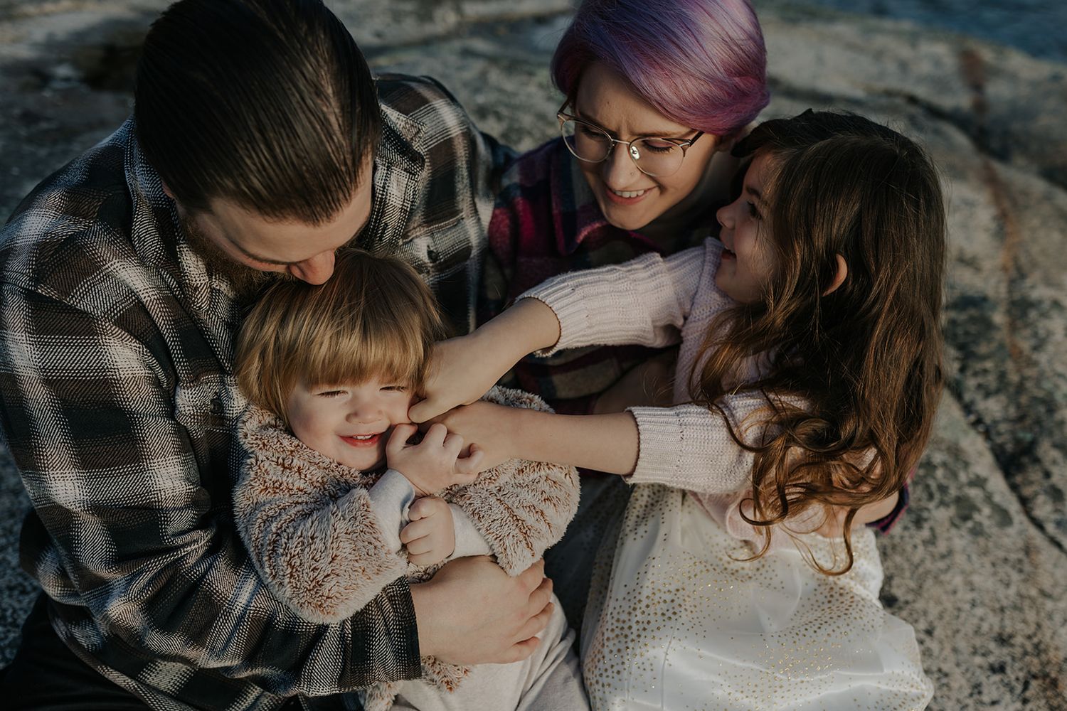 A family shares an intimate moment together on rocky terrain during a photo session.