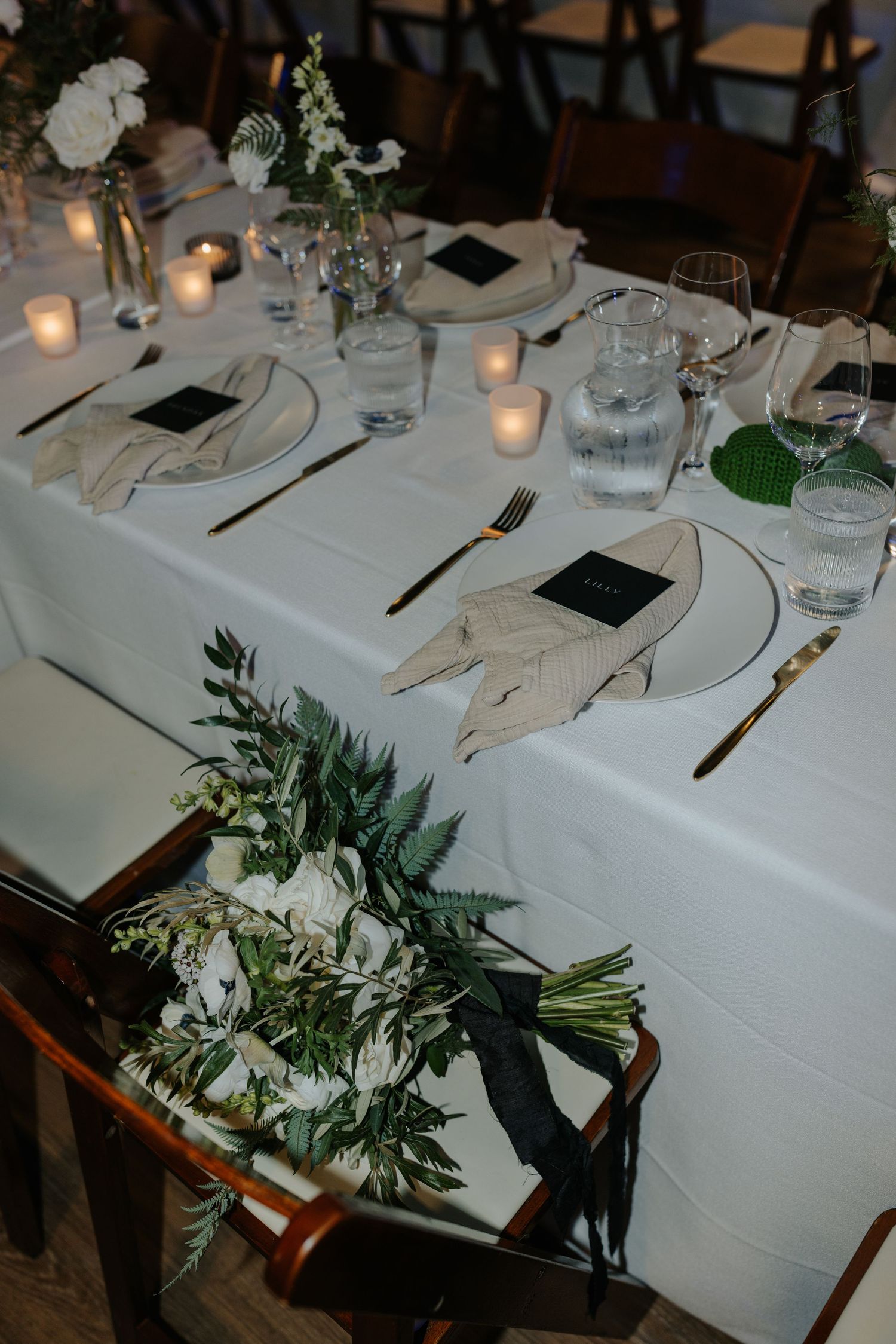 Elegant wedding reception table settings with white linens, glassware and delicate floral centerpieces.
