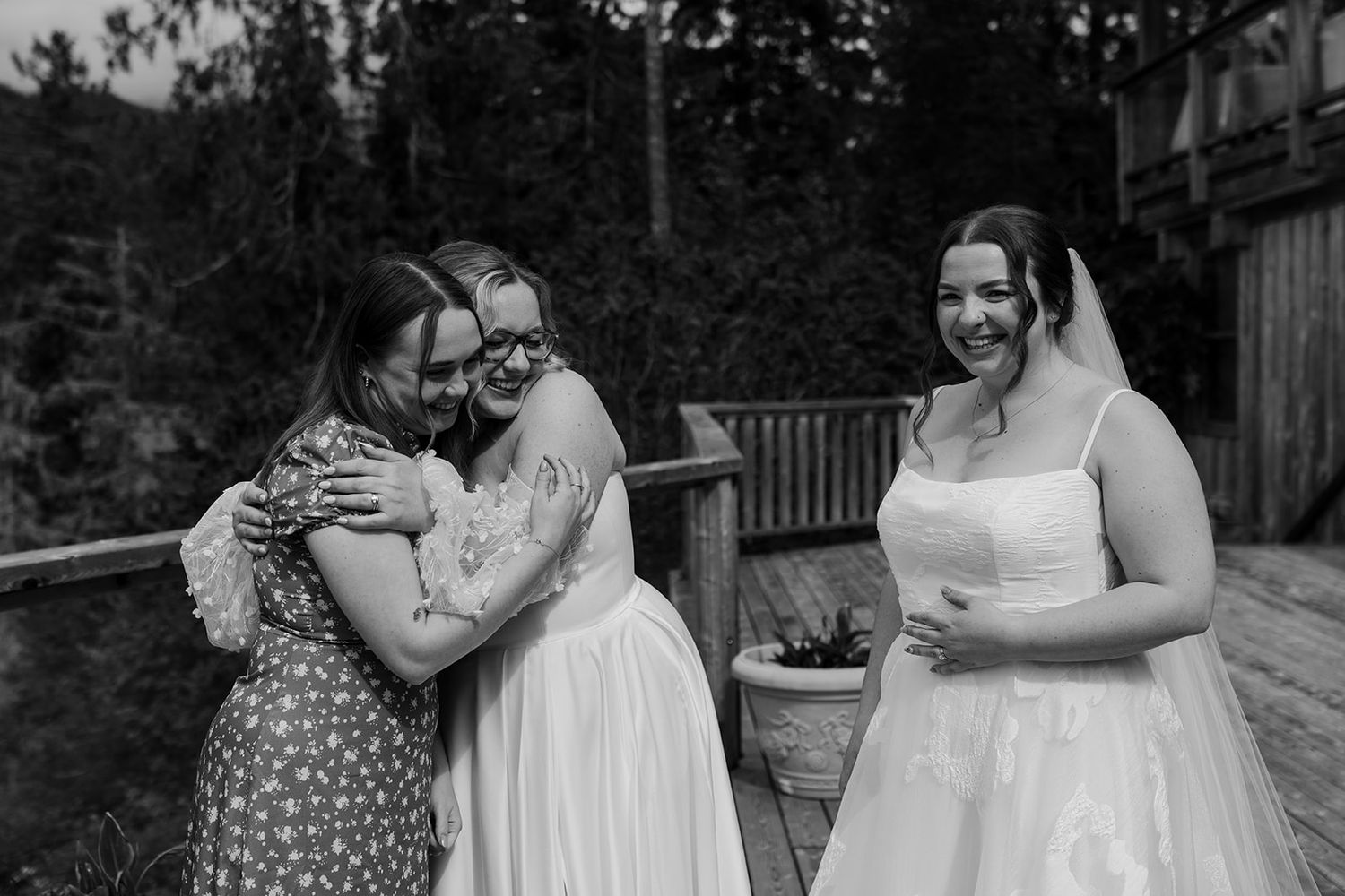 Wedding party members share emotional embraces during an outdoor celebration.