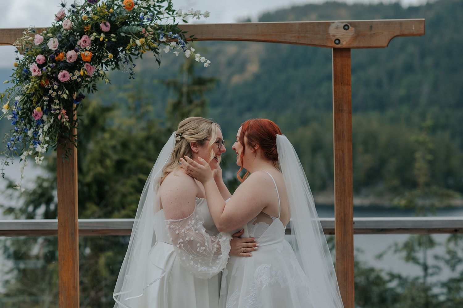 Wedding ceremony setup with wooden arch and mountain lake backdrop.