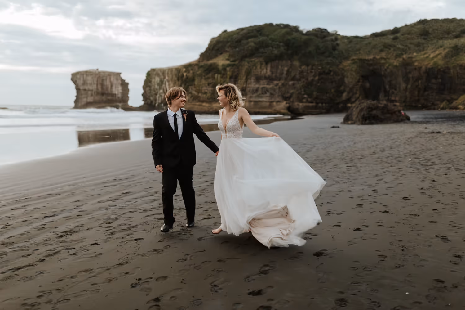 couple running along the beach for their wedding photos looking joyful and carefree