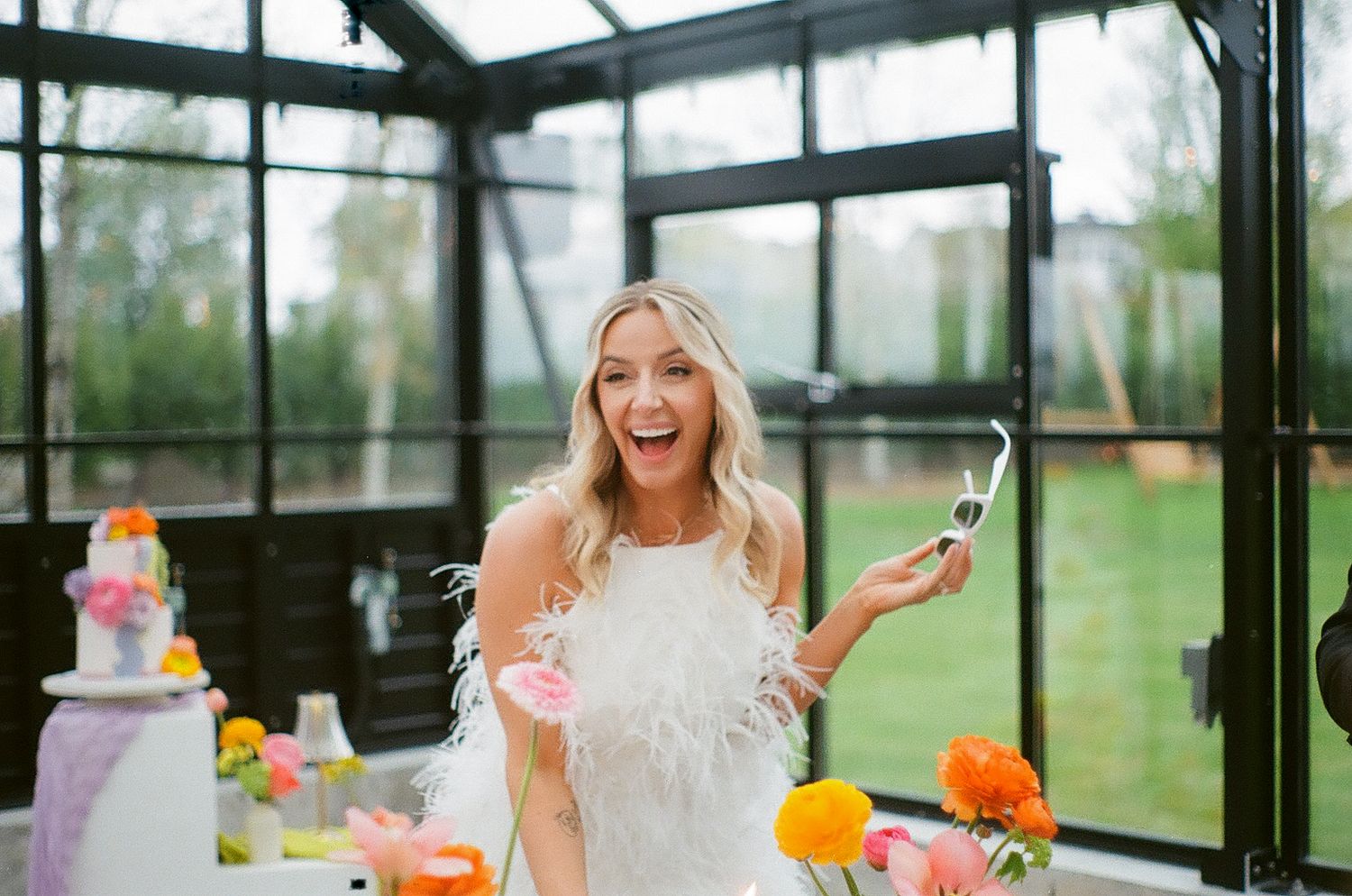 Joyful celebration inside a glass-enclosed venue with orange and pink floral decorations.
