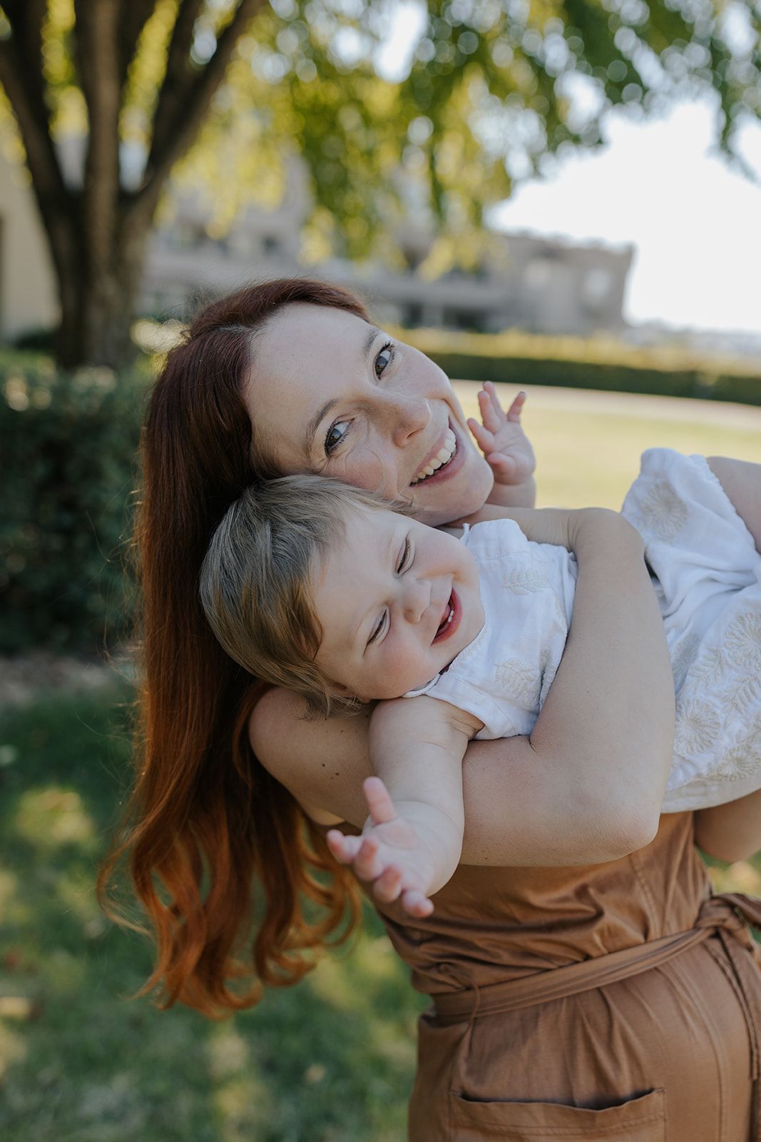 Playful moment shared between parent and child in sunny garden setting.