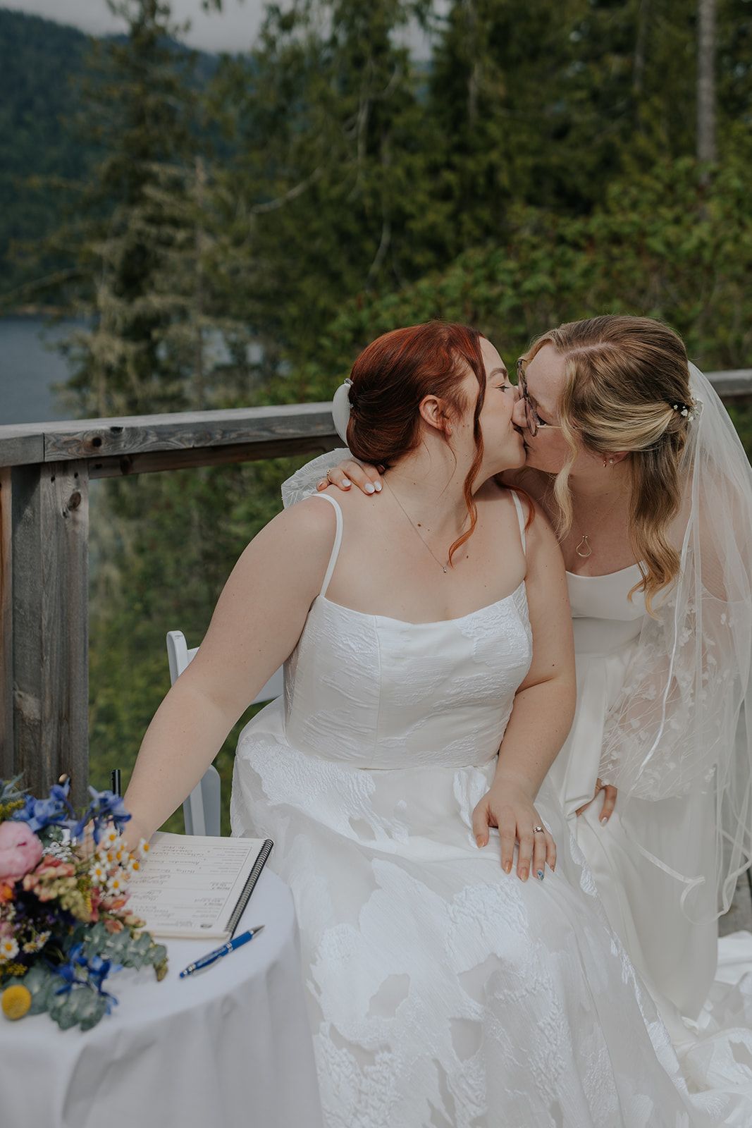 Intimate moment captured during document signing at an outdoor wedding ceremony.