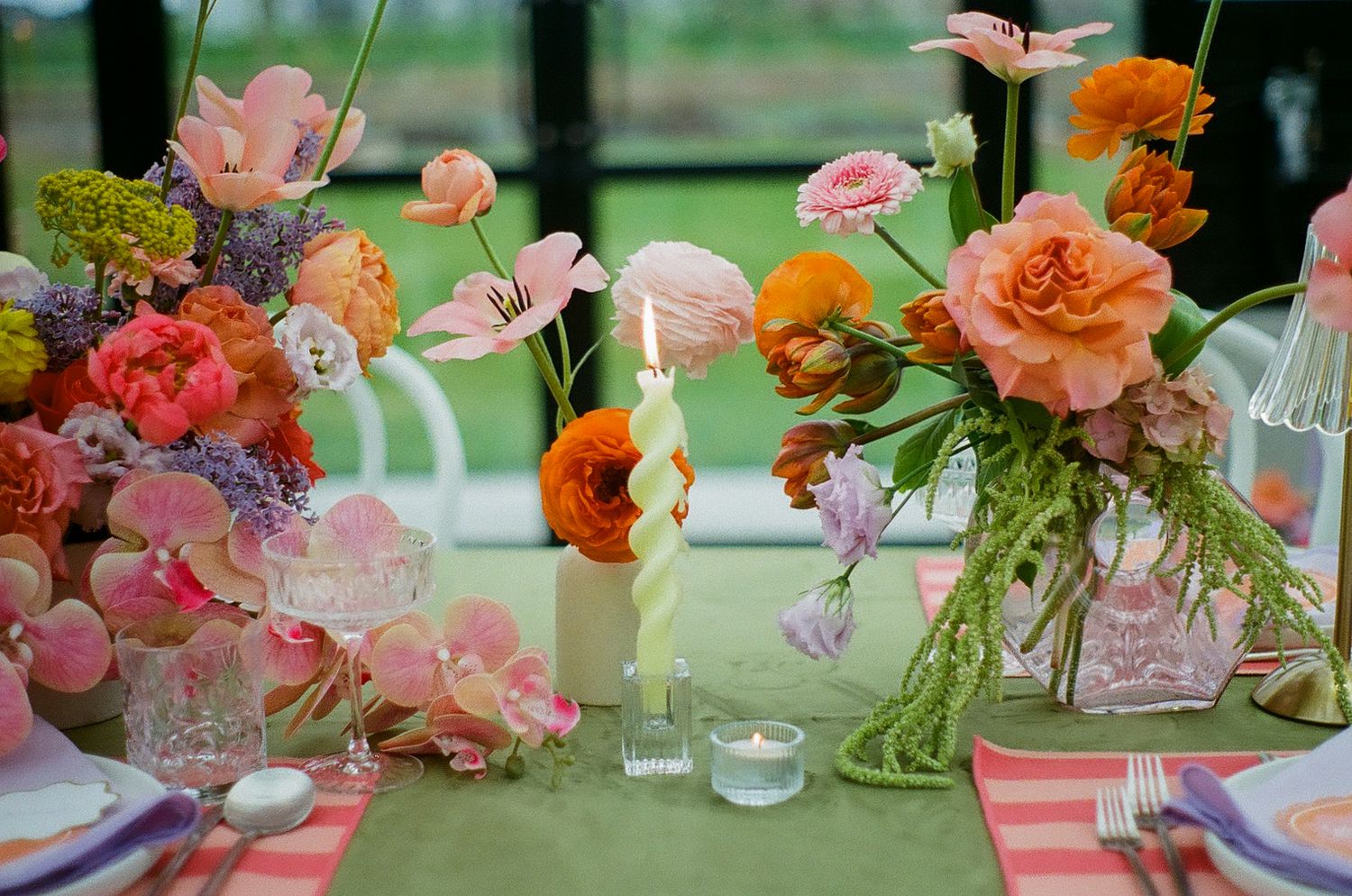 Wedding reception table decorated with vibrant coral and pink flower arrangements.