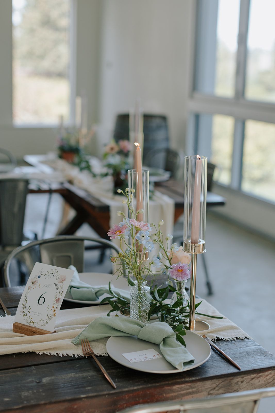 Elegant wedding table setting with candles, greenery and place cards.
