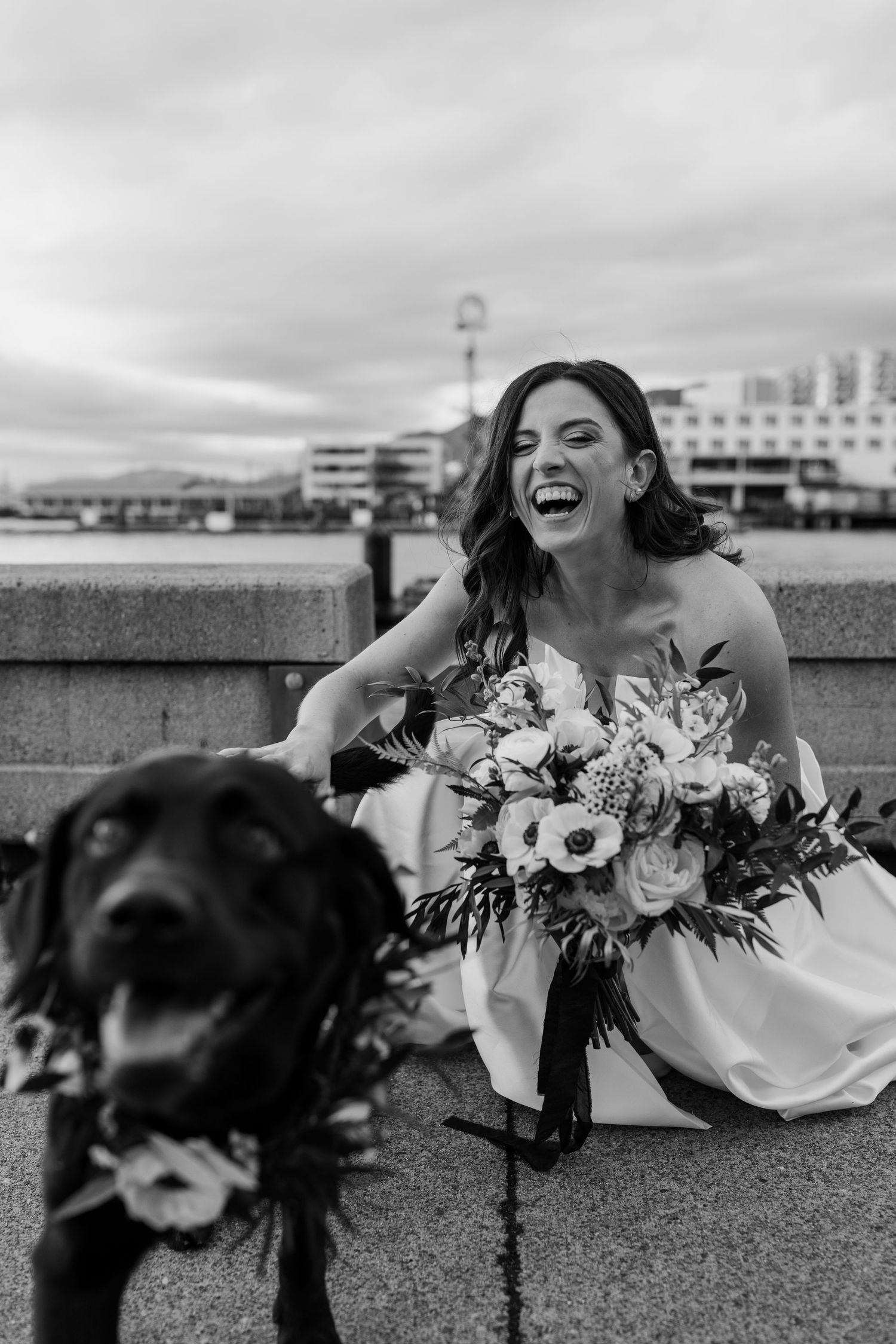 Candid black and white photos of joyful moments with wedding bouquets by stone wall.