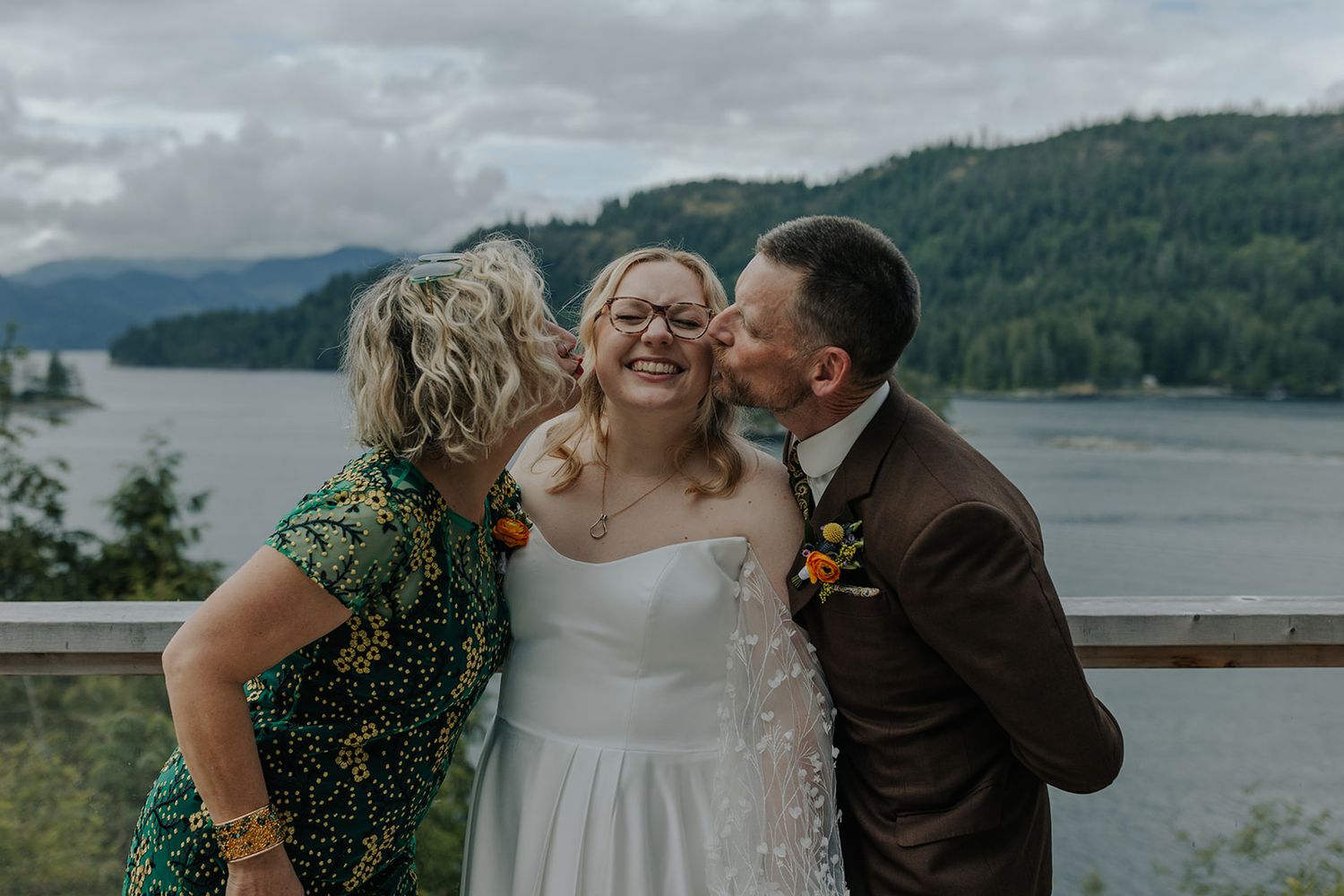 Joyful moment shared against scenic mountain lake backdrop at outdoor wedding.