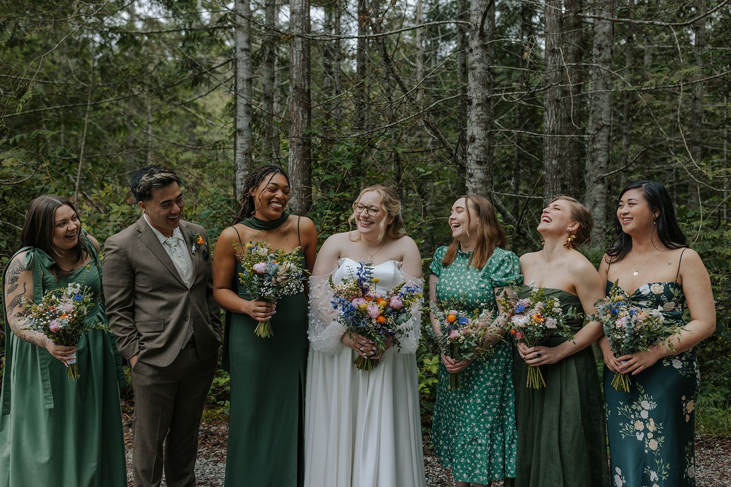 Candid moments of wedding party interacting on forest path in green and white attire.