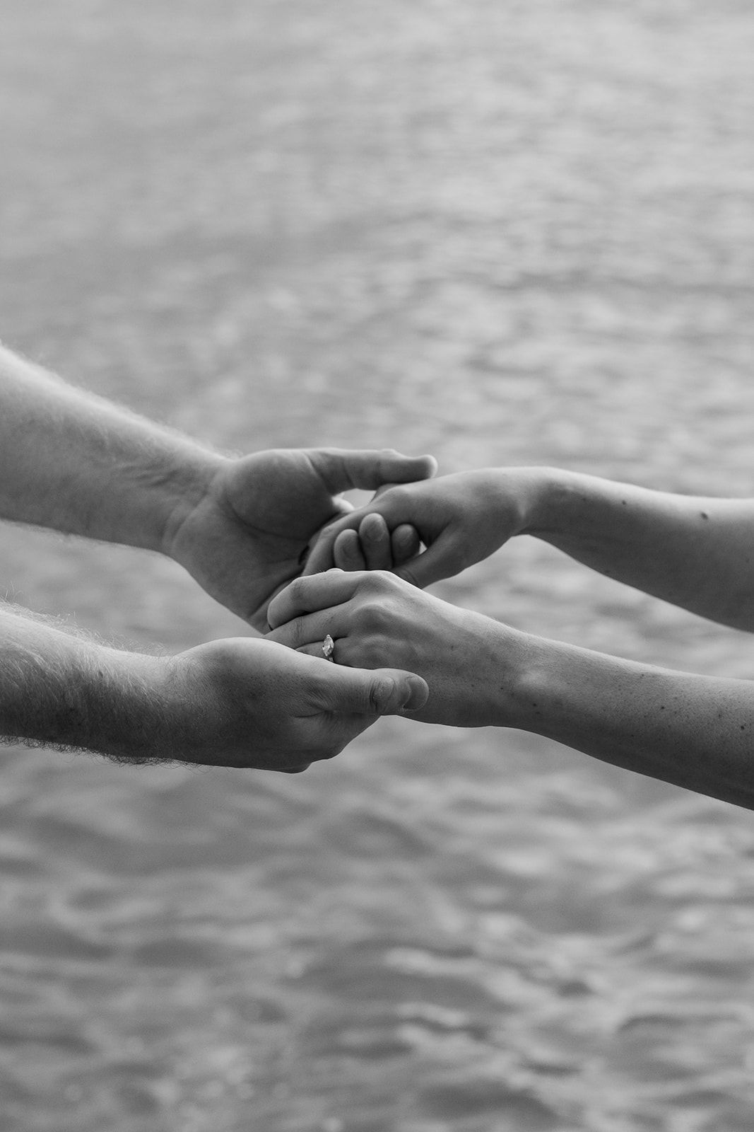 Black and white image of two hands reaching towards each other in a tender moment.