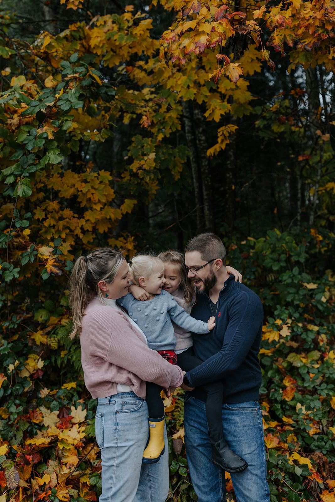 Family embracing outdoors against beautiful autumn foliage.
