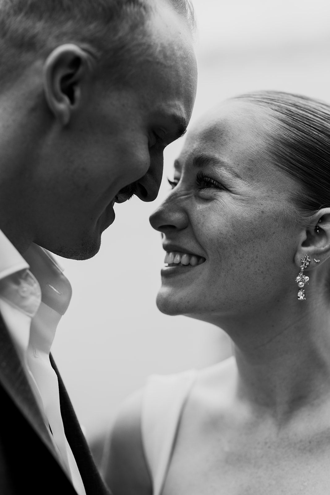 An intimate black and white portrait of a couple sharing a close moment.