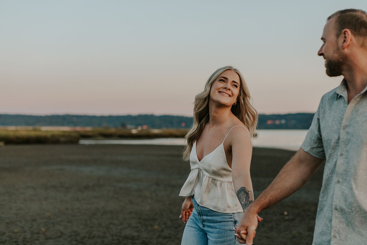 A couple dances and laughs together in an open field during golden hour.