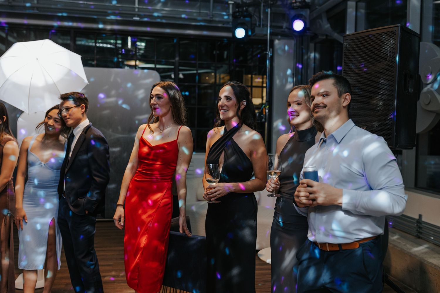 Wedding party guests mingling and socializing in formal attire at an evening reception.