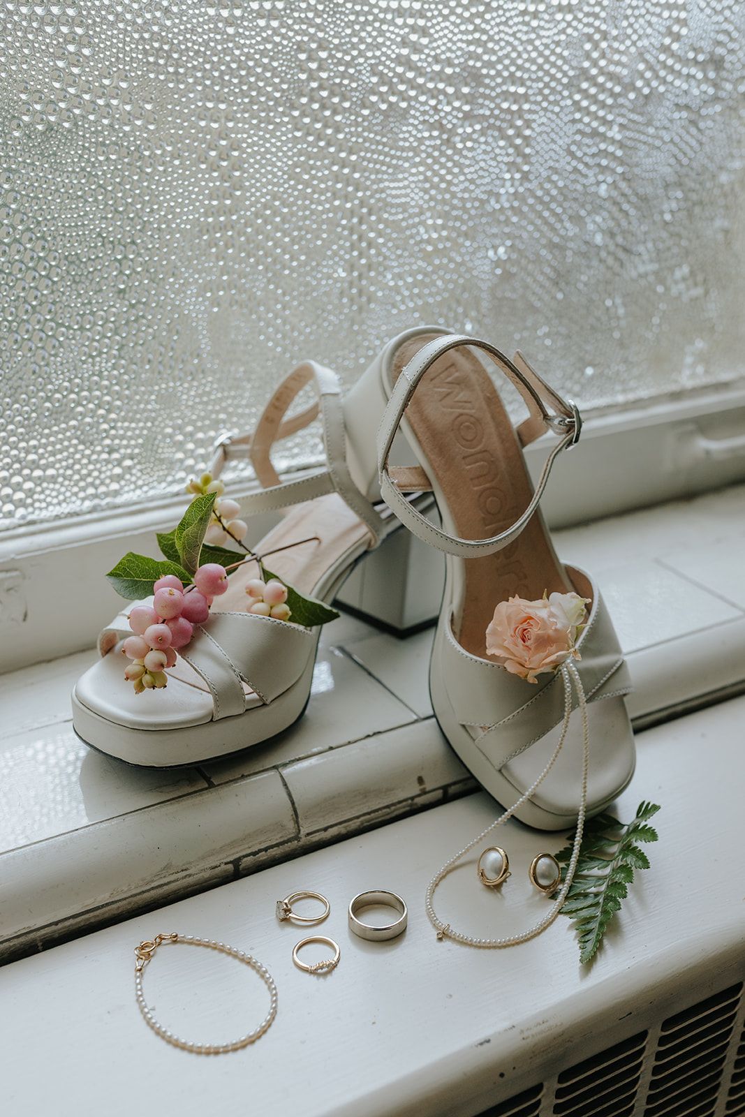 Wedding accessories and jewelry arranged on a misty windowsill with delicate flowers.