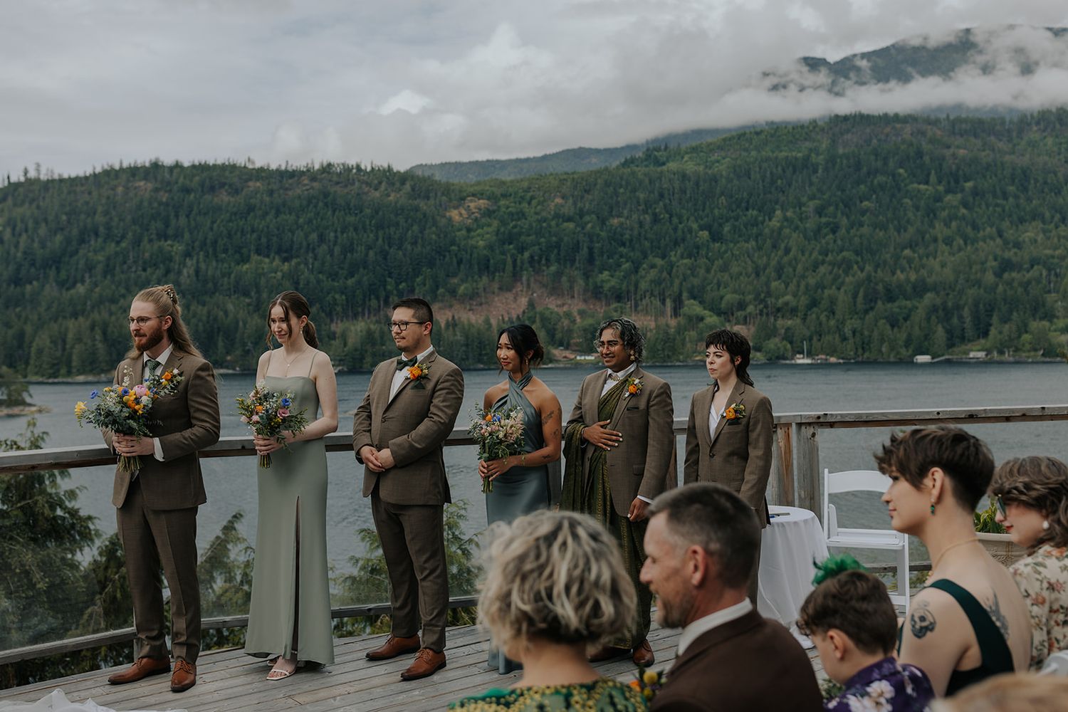 Panoramic view of wedding guests gathered at outdoor ceremony overlooking mountain landscape.