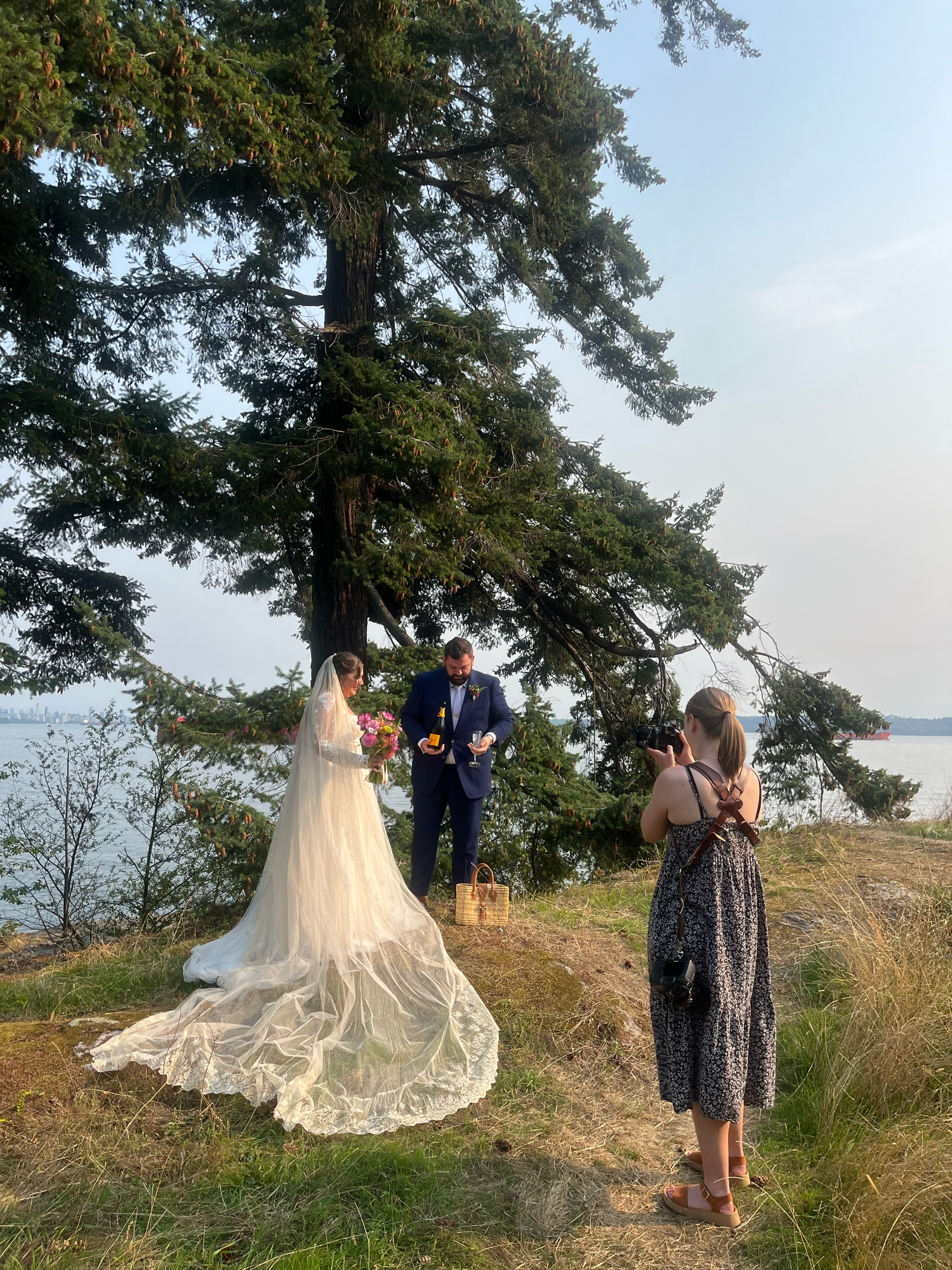 Outdoor wedding photography session on a hilltop overlooking water with flowing white dress.