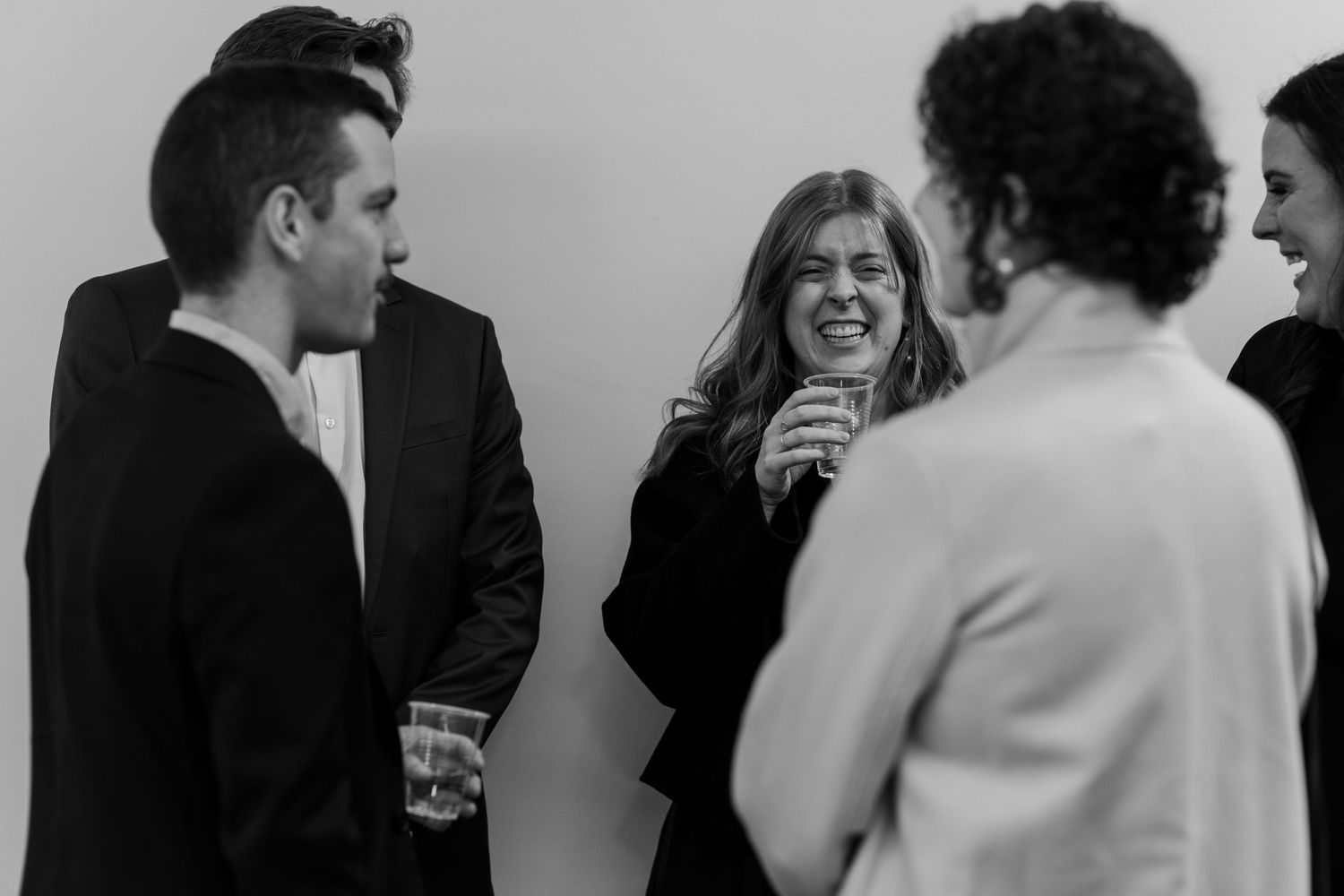Wedding reception guests mingling and laughing at indoor celebration.