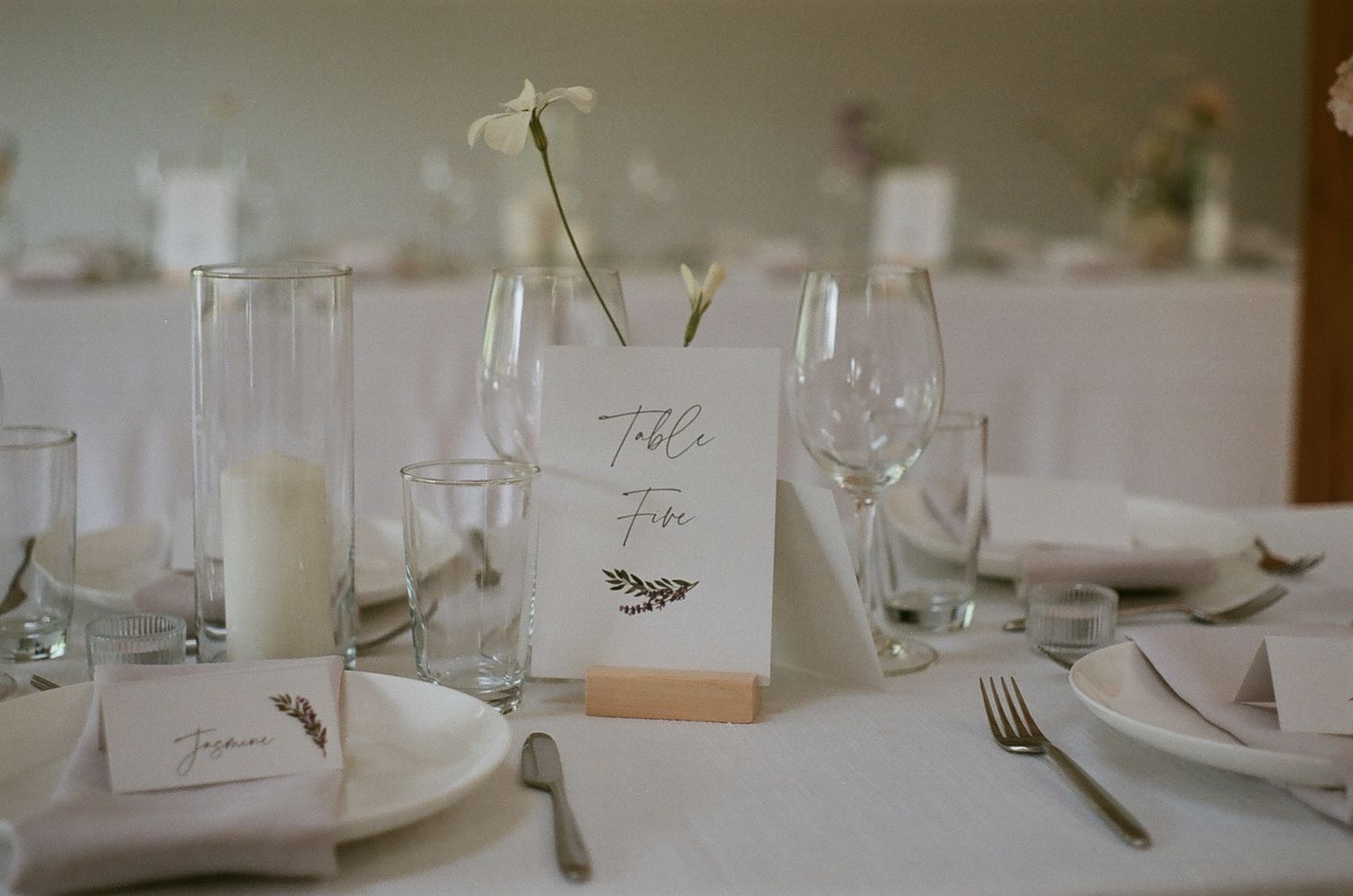 An elegant wedding table setting with white linens and place cards.