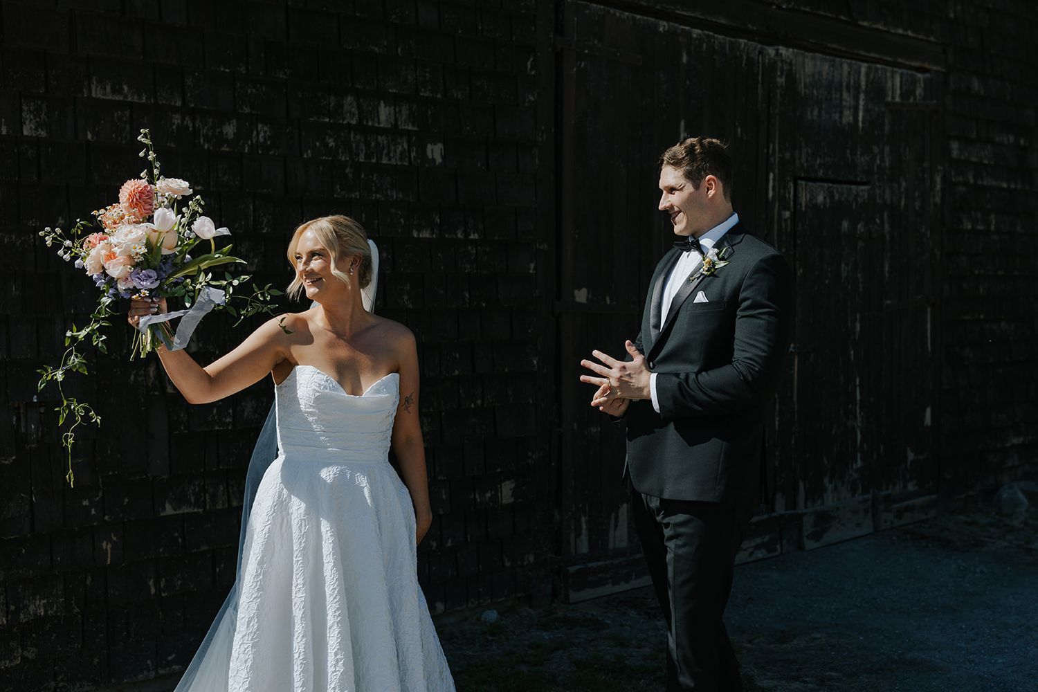 A couple shares a candid moment against a dark wall during their wedding photoshoot.