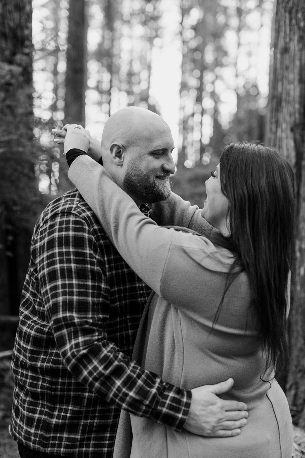 An intimate sequence of embraces captured in black and white against a forest backdrop.