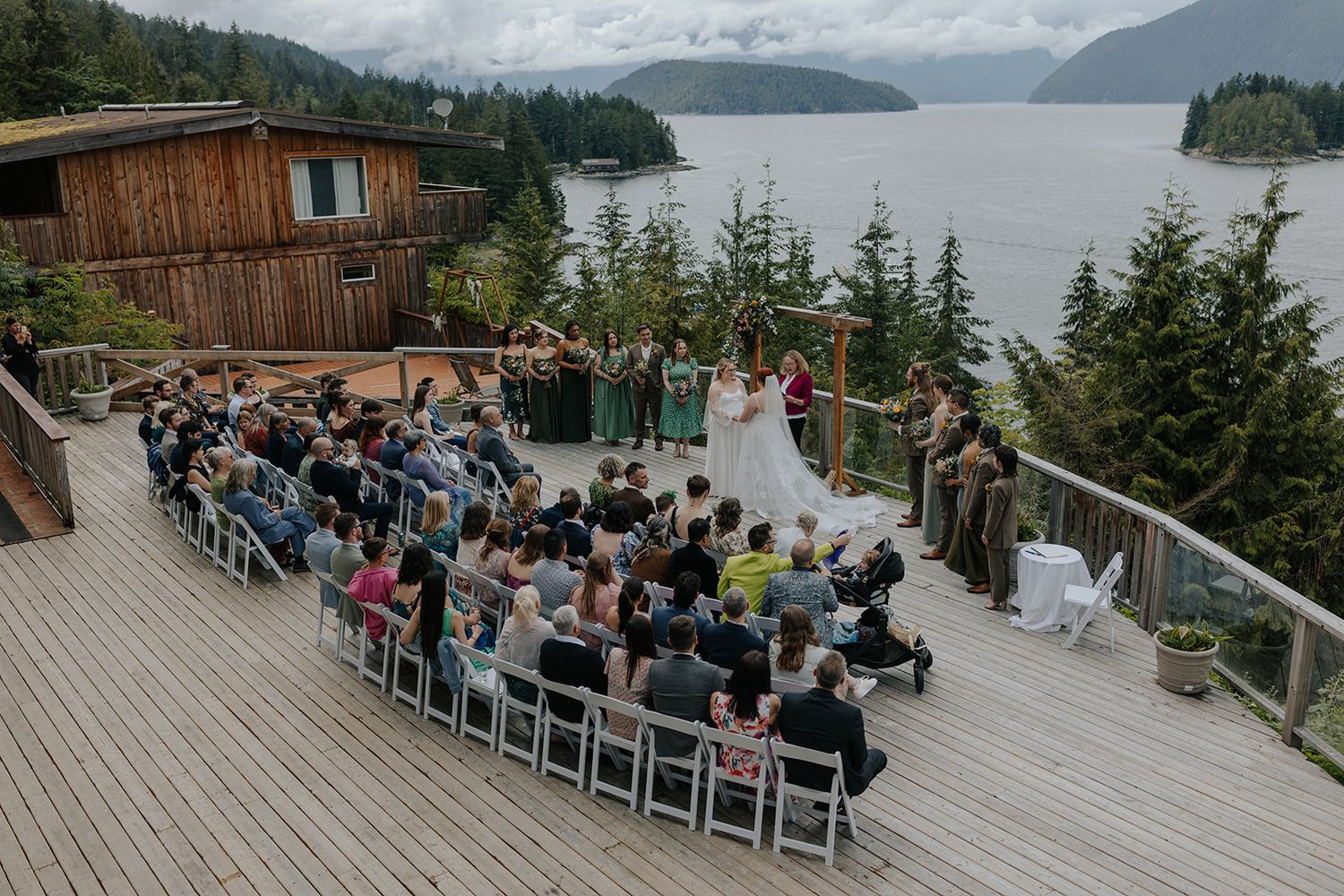 A scenic outdoor wedding ceremony setup on a deck overlooking mountains and water.