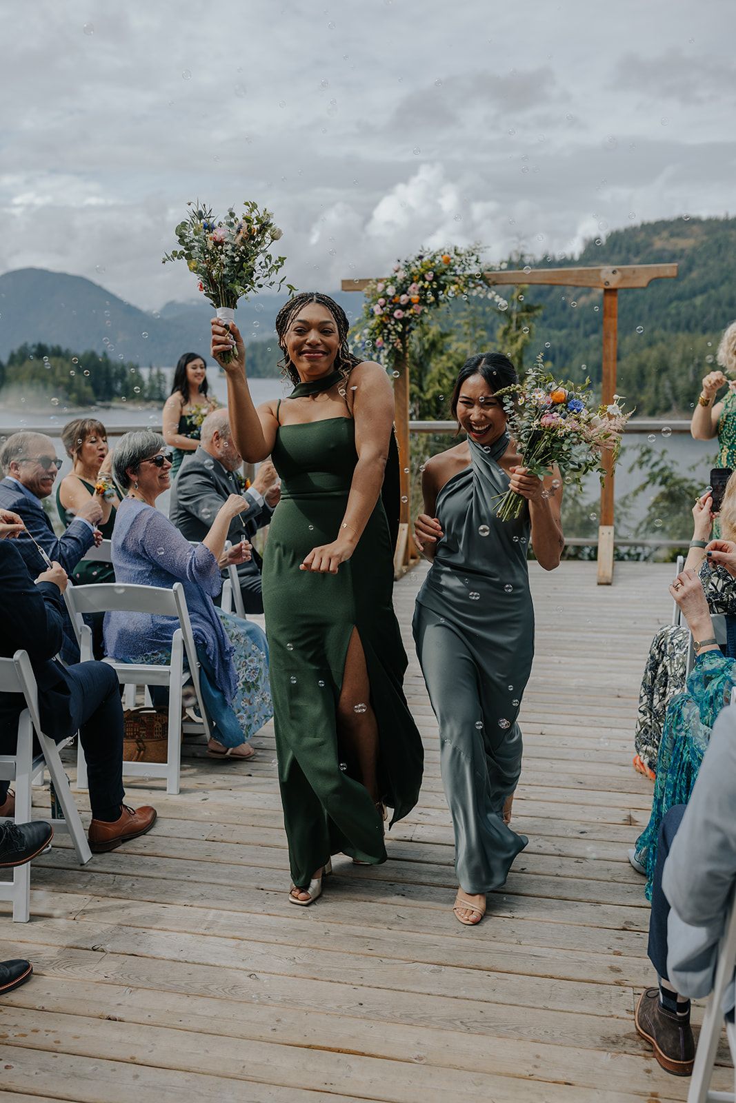 Wedding party members perform choreographed dance moves on outdoor wooden deck.