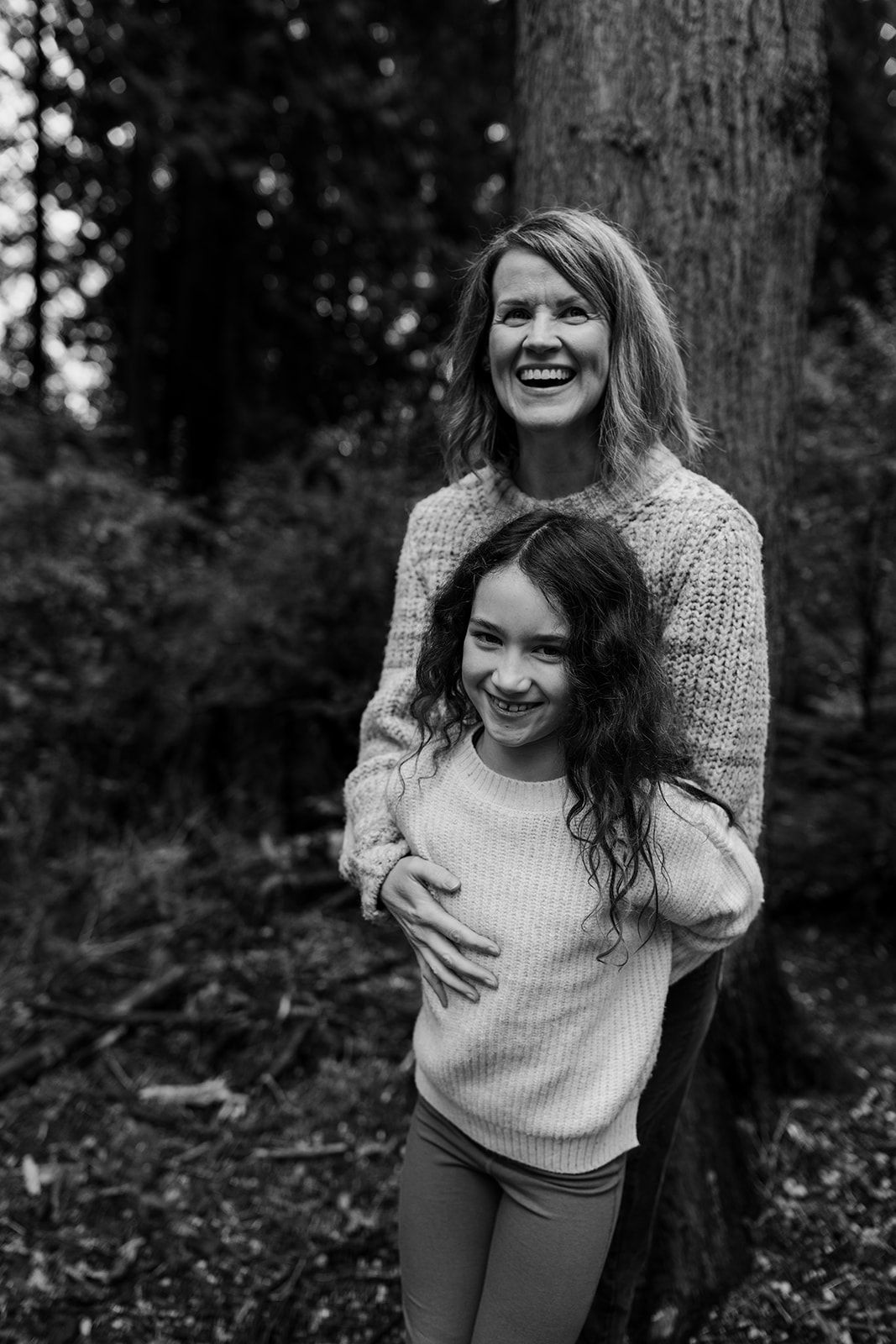 Candid black and white photos of joyful moments between two people in a forest setting.