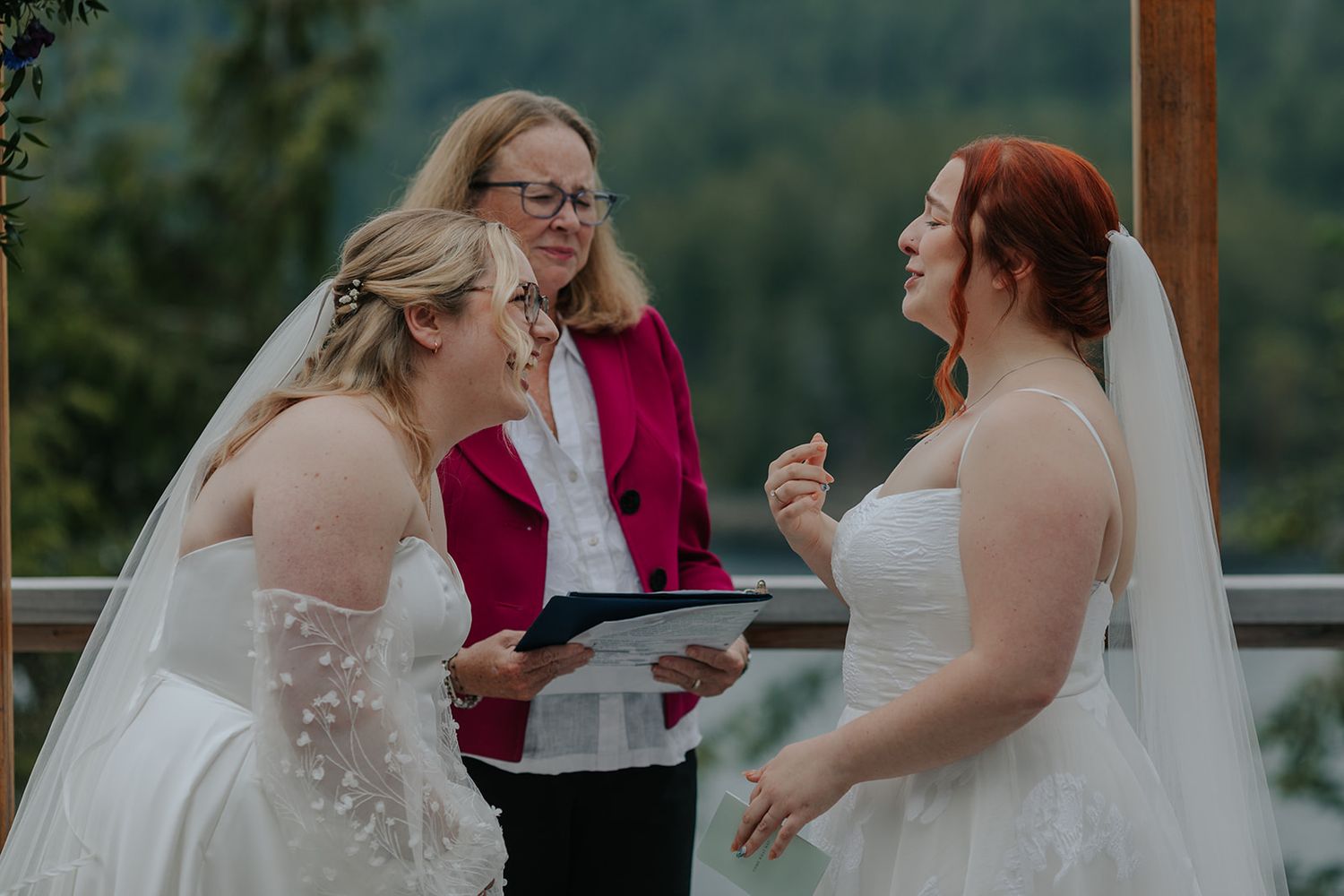Outdoor wedding ceremony with officiant in pink and bride in white against mountain backdrop.