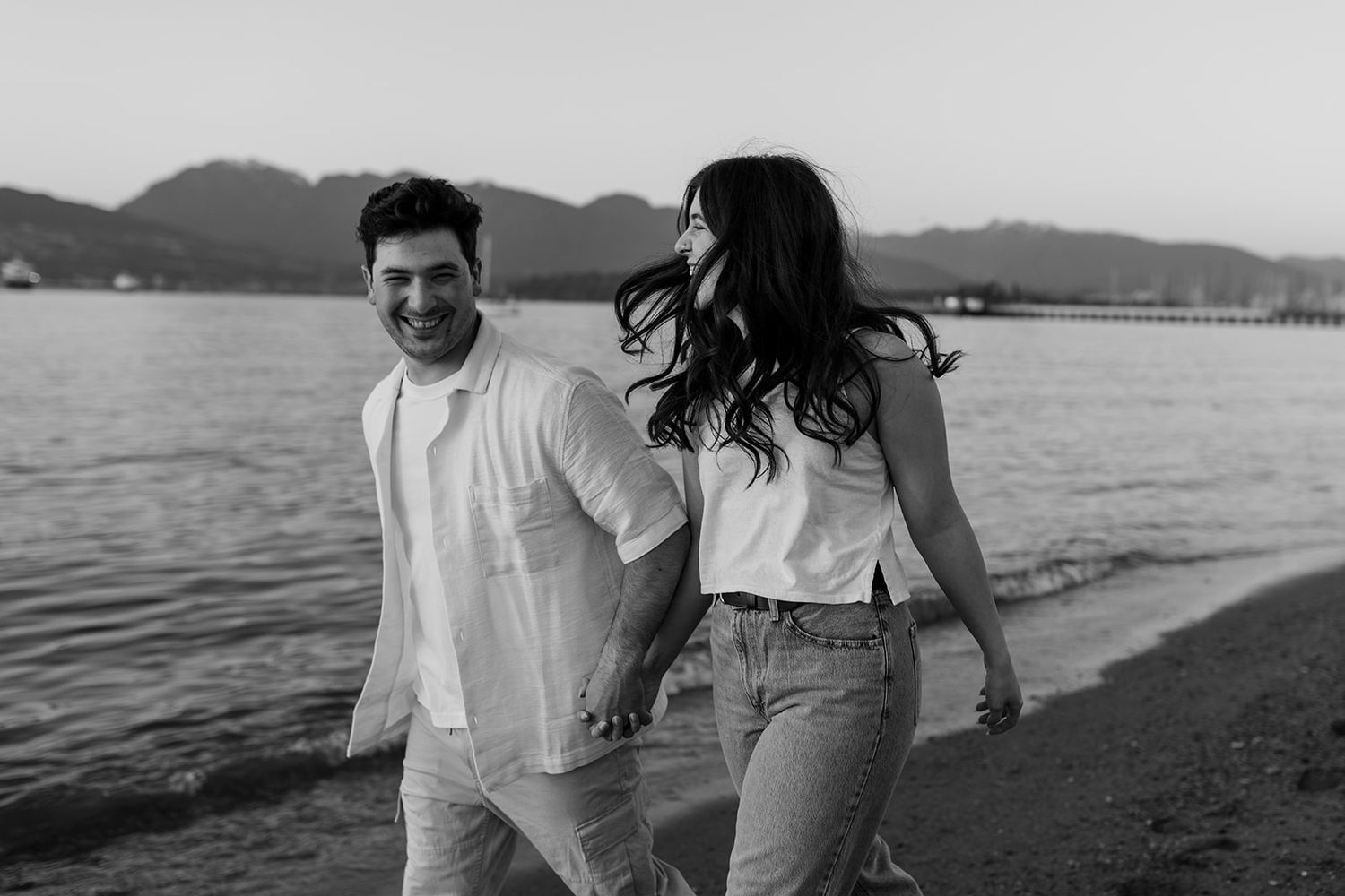 A couple walks along a scenic beach at sunset, holding hands and enjoying the peaceful moment together.