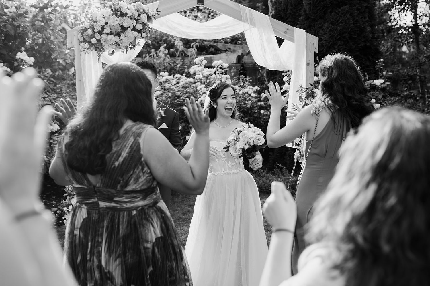 Black and white photo of joyful wedding celebration with guests dancing.