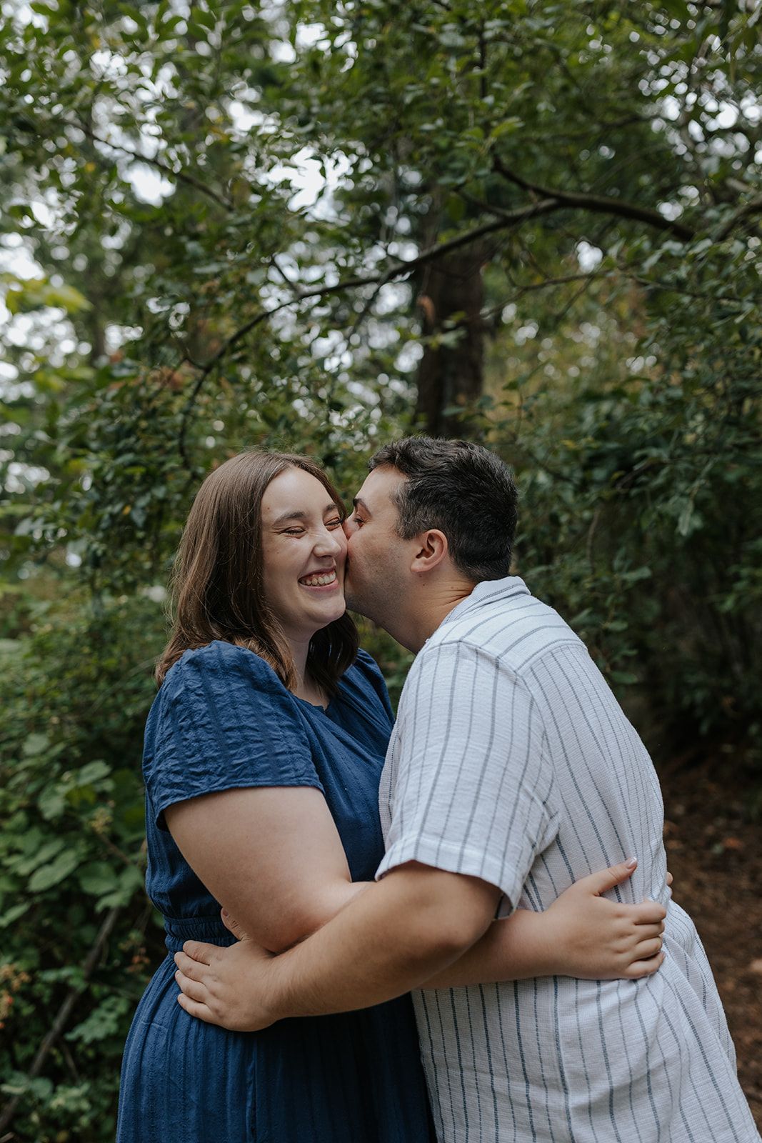 A playful embrace captured in a natural outdoor setting with greenery.