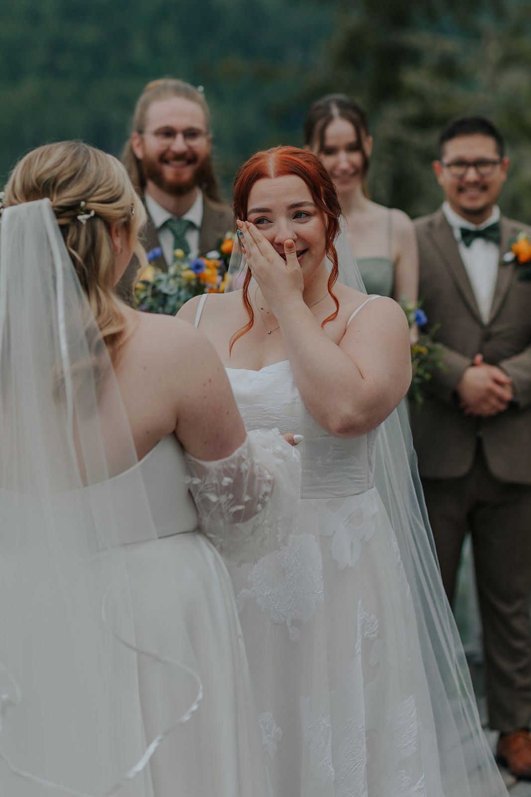 Emotional wedding ceremony moment captured outdoors with mountain scenery.