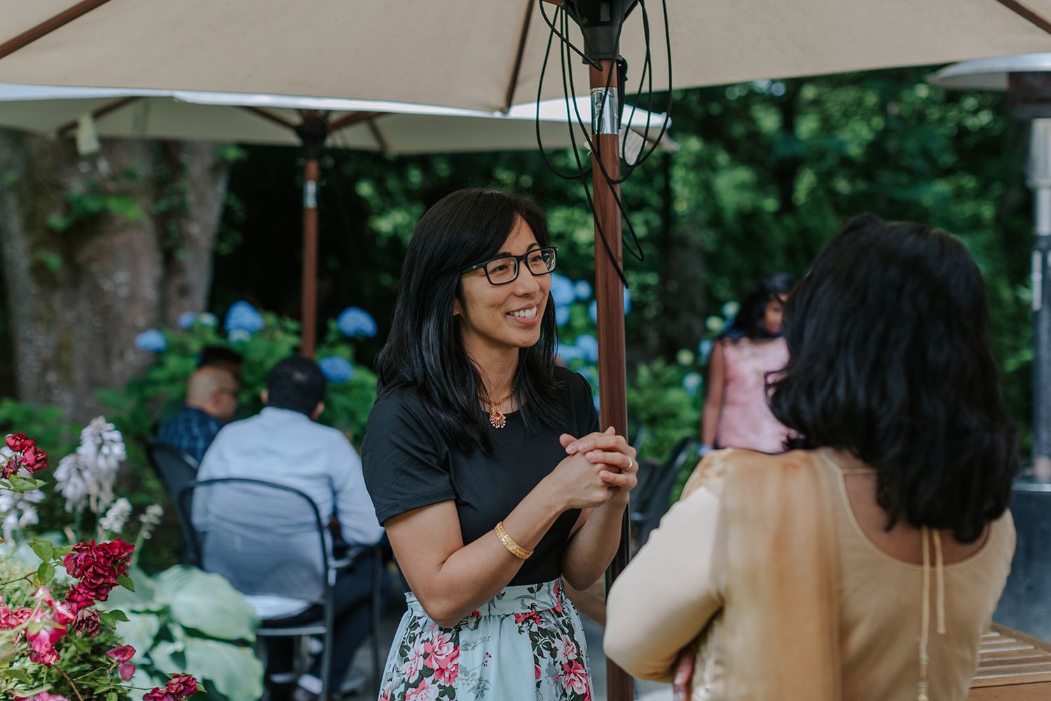 People gather outdoors under umbrellas during a social event.