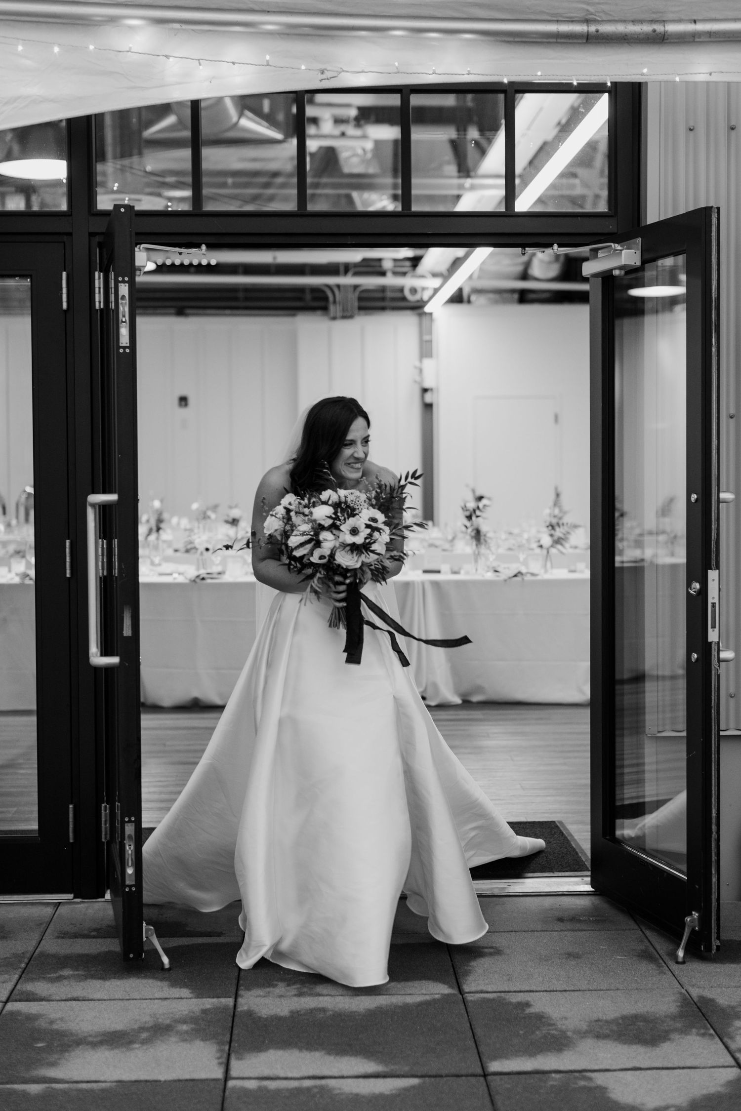 Black and white photo of wedding decor with white tablecloths in an industrial space.