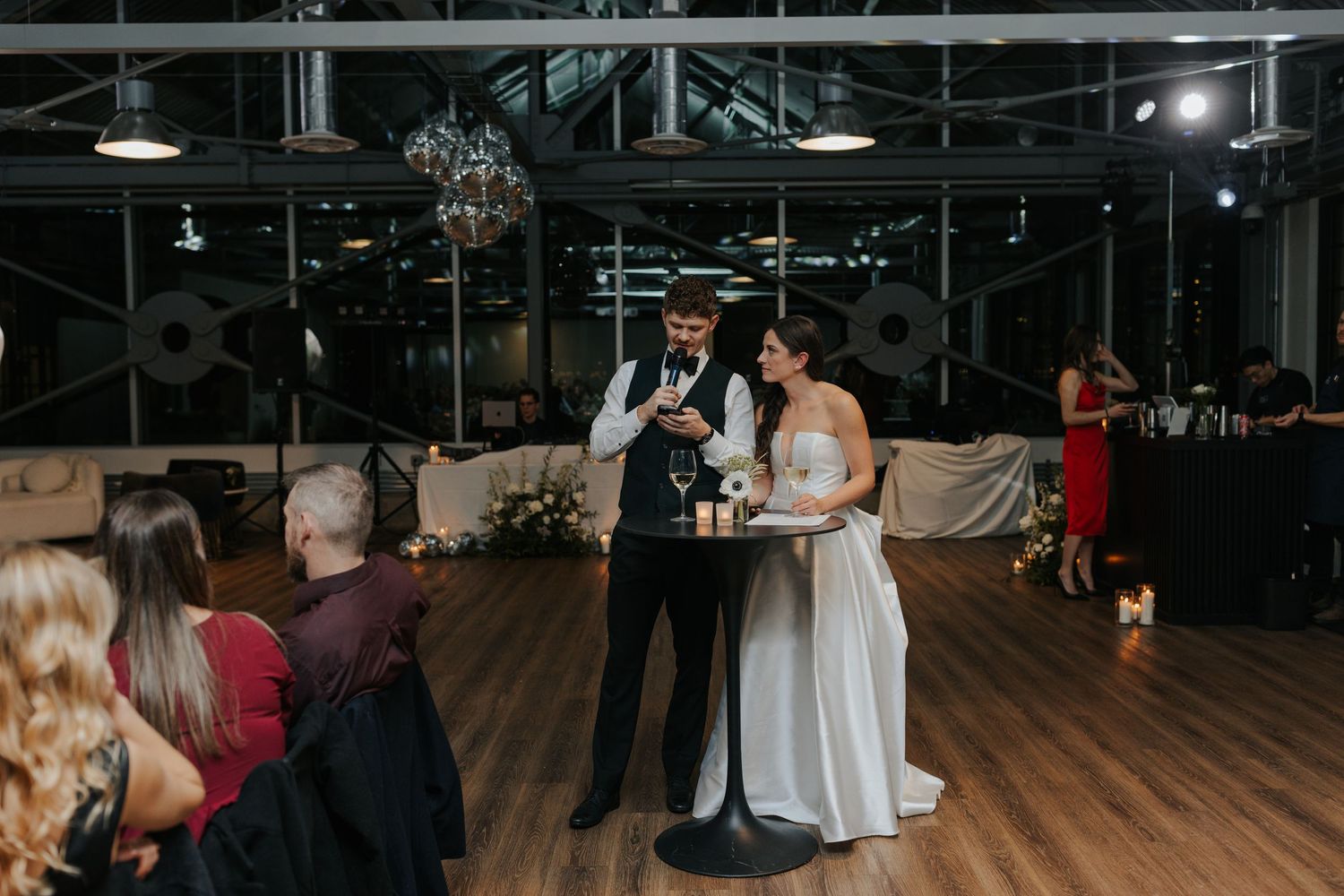 Panoramic view of wedding guests dancing and celebrating in an industrial-style venue.