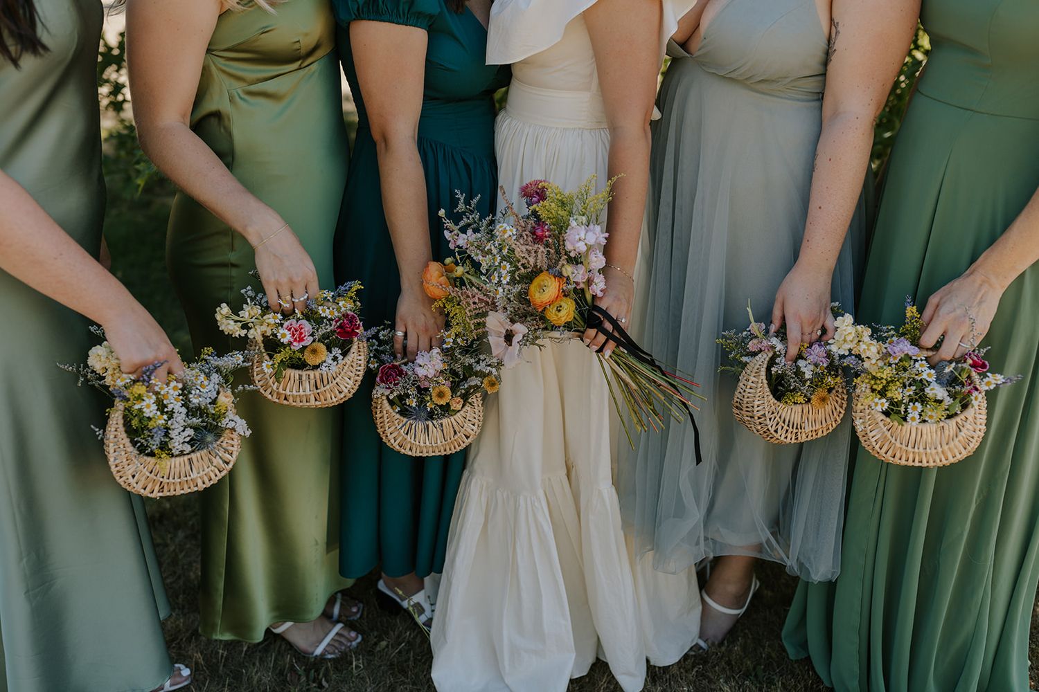 Bridesmaids in sage green dresses holding floral bouquets.