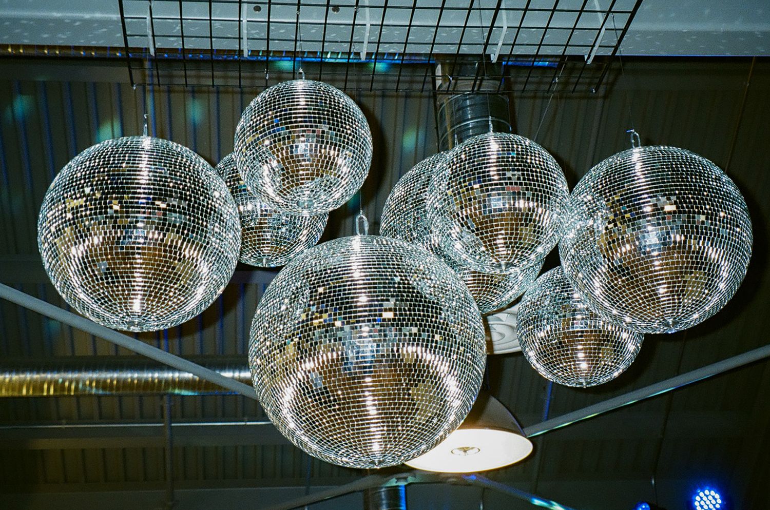 Multiple disco balls hanging from ceiling create sparkling party atmosphere.