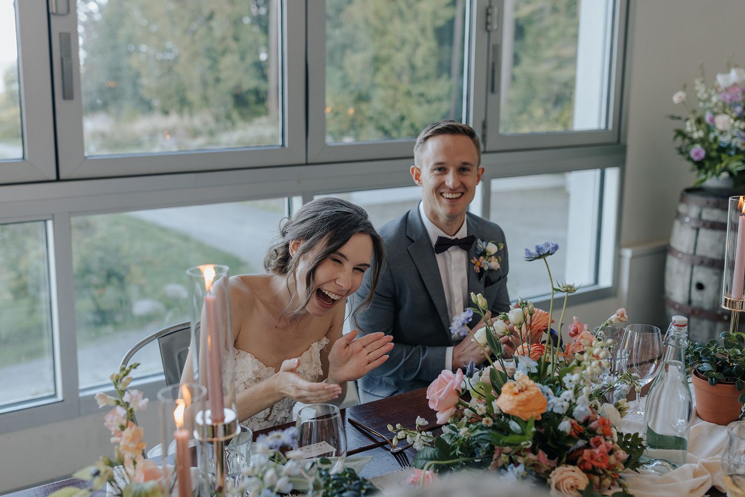 Modern reception venue with large windows overlooking mountain scenery and decorated dining tables.