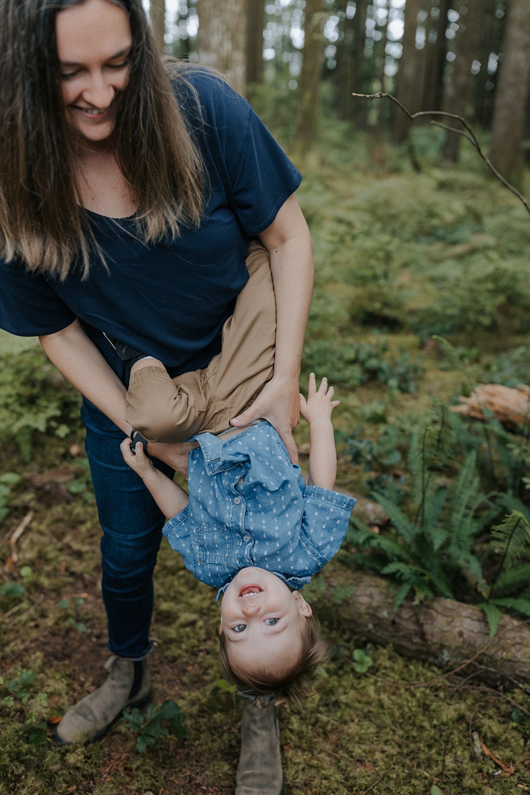 Playful sequence of holding and flipping a child upside down in a forest setting.