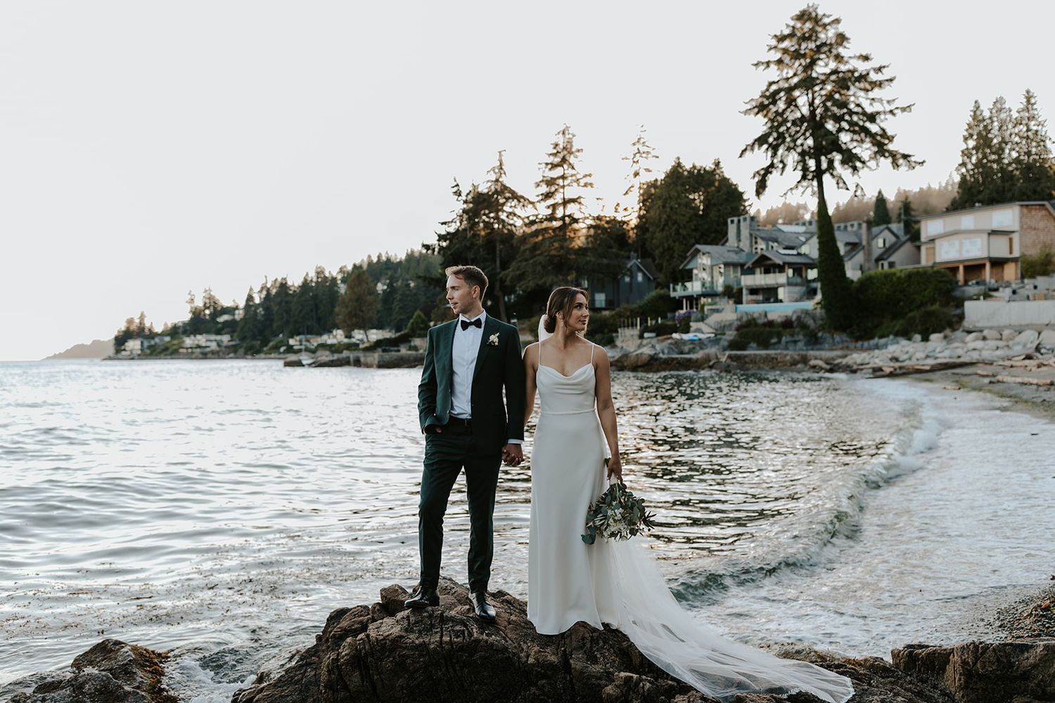 Scenic coastal wedding photography with evergreen trees and ocean backdrop.