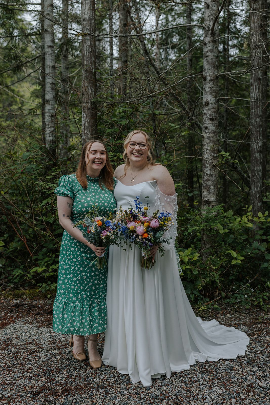 Two people share a joyful moment in a forest clearing while holding vibrant wildflower bouquets.