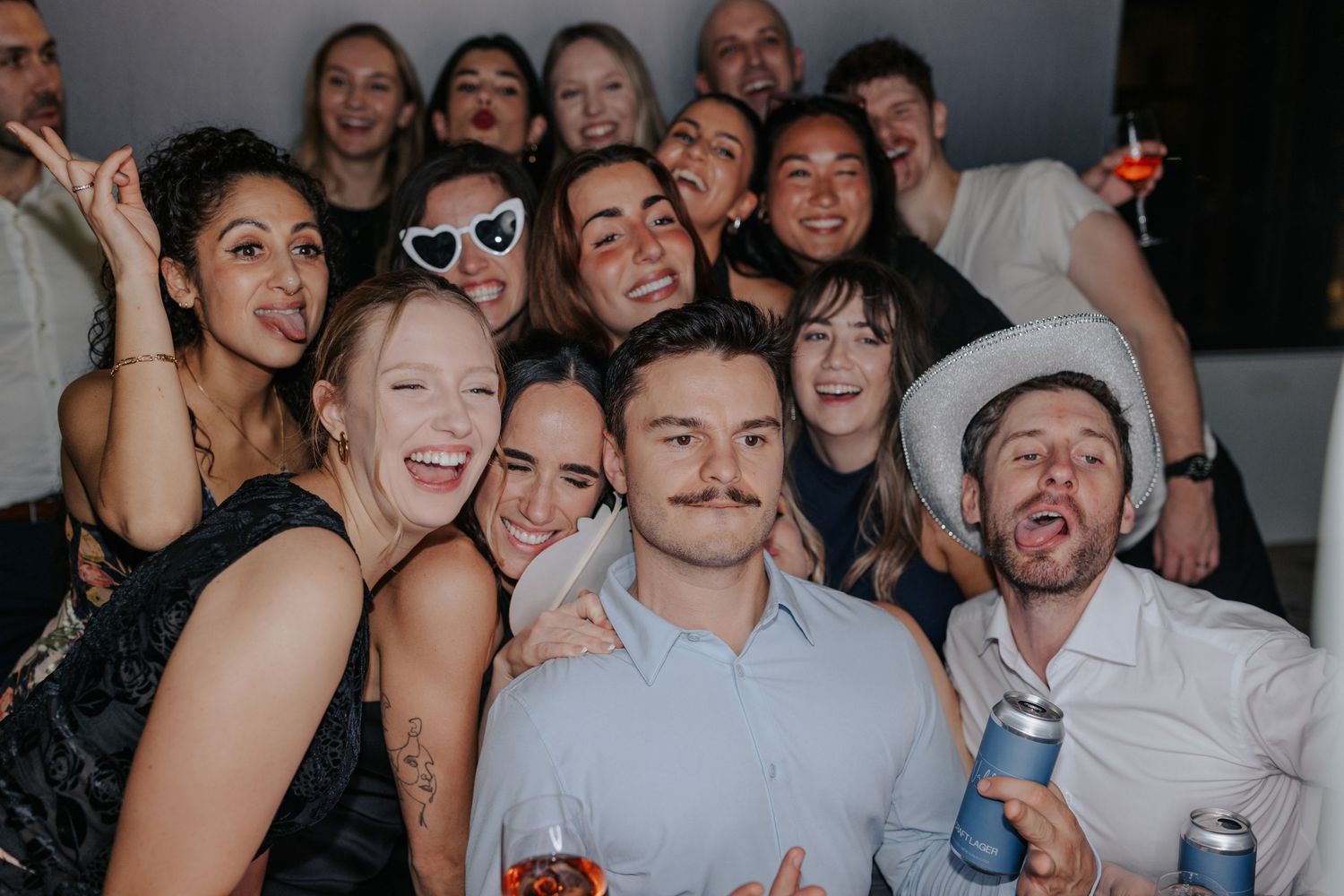 Group of wedding guests pose together for a fun candid photo at the reception.