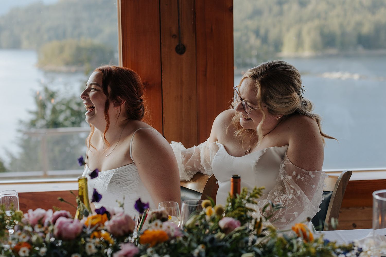 Wedding reception table decorated with floral arrangements overlooking waterfront view.
