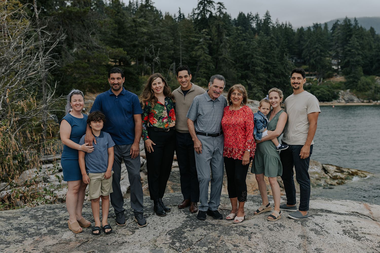 Extended family group portraits taken at a scenic lakeside location with mountains in background.