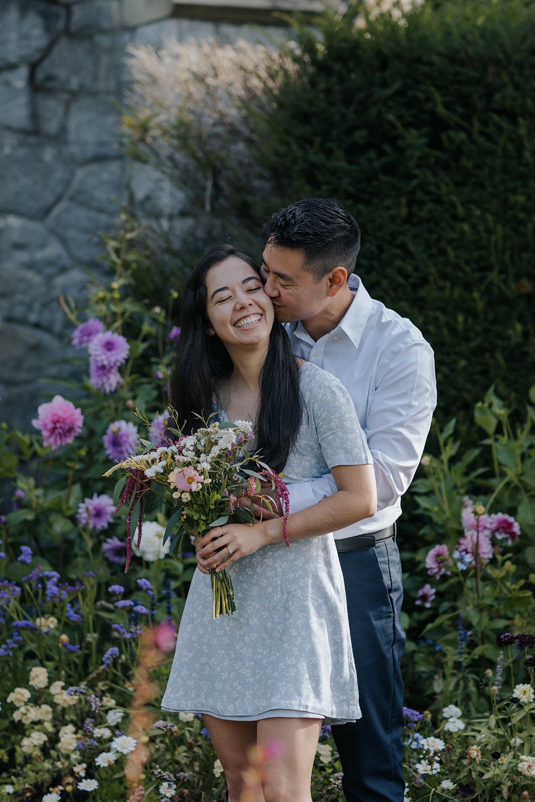 A couple shares romantic moments in a garden with blooming purple flowers.