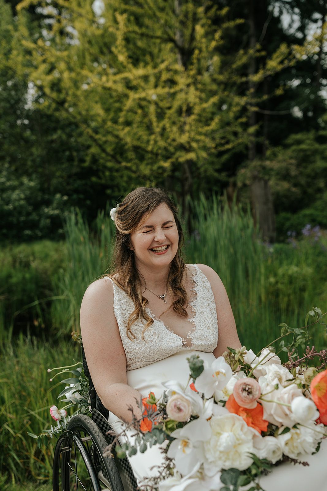 Wedding portrait with lush bouquet featuring white and orange blooms in garden setting.