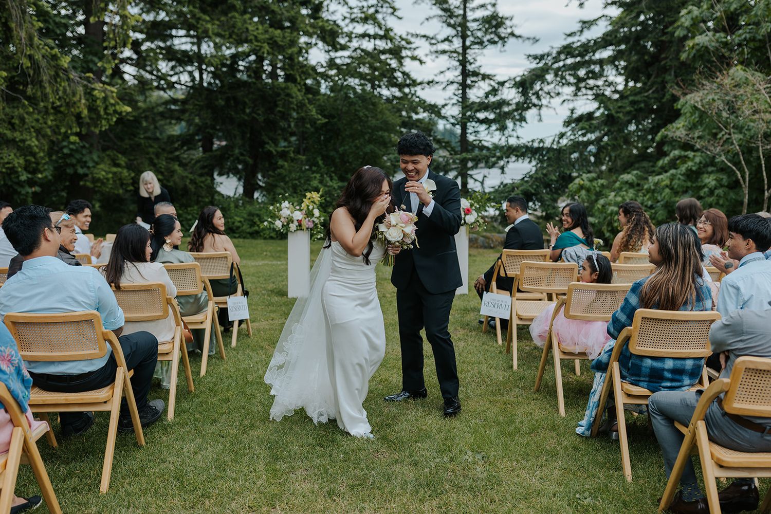 Outdoor wedding ceremony setup with wooden chairs arranged on a grassy hillside.